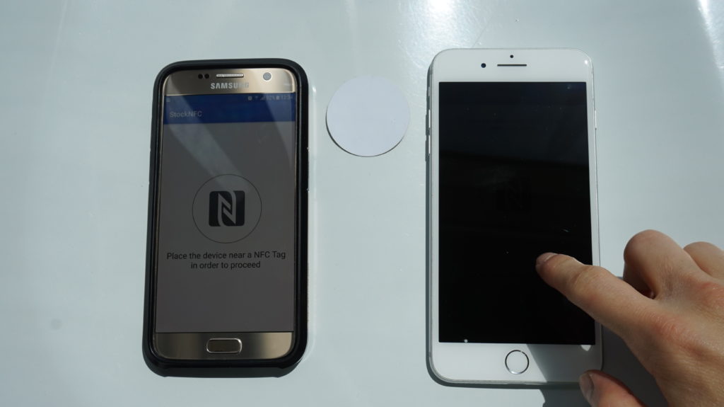 Samsung phone with NFC tag reader and iPhone with hand tapping iPhone screen